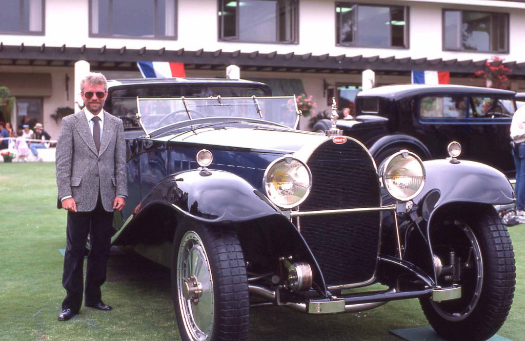 Derek Bell standing beside the famed Coupe Napoleon at Pebble Beach in 1985.